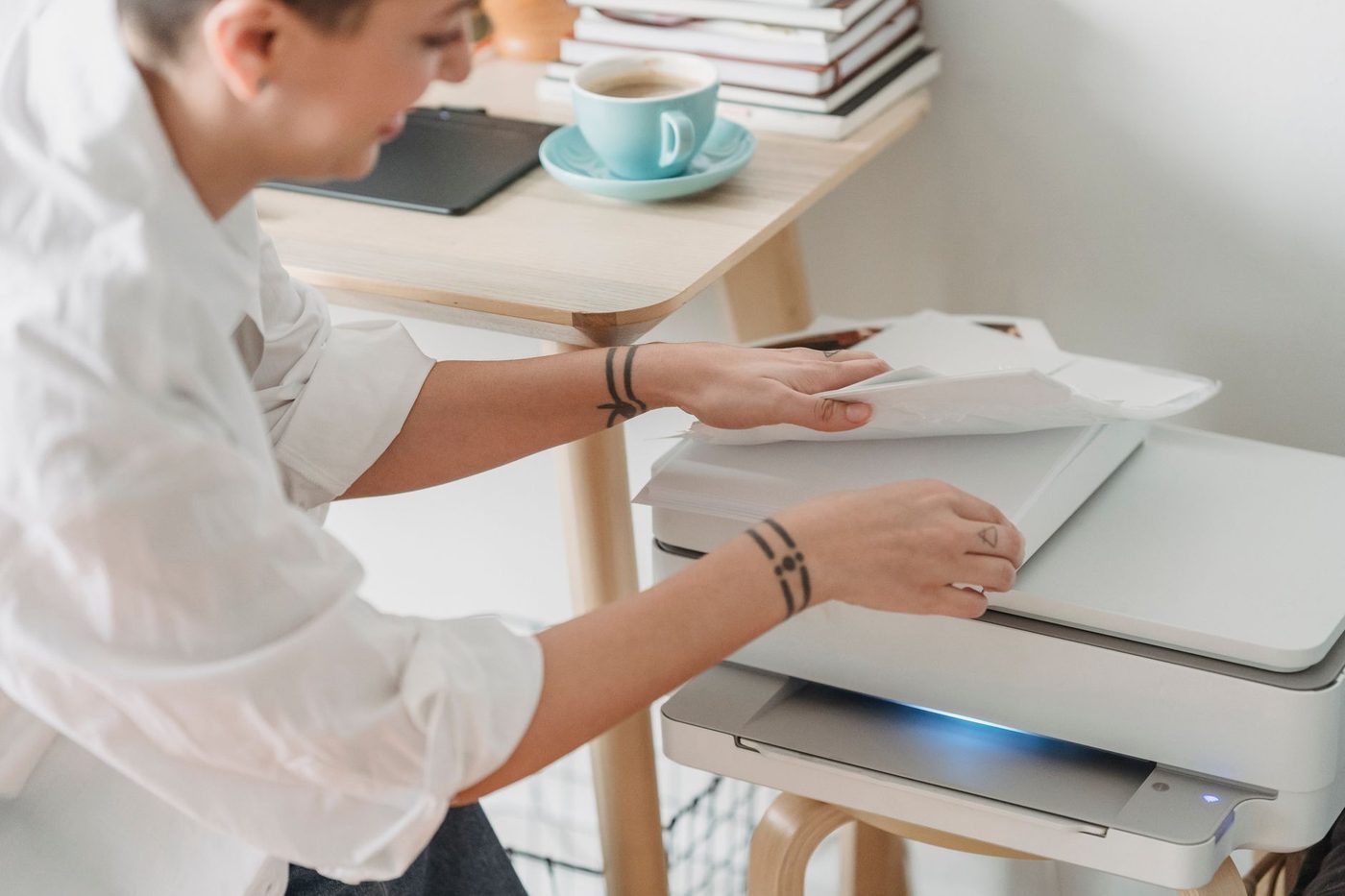 Someone taking printed sheets from a printer on a small wooden desk