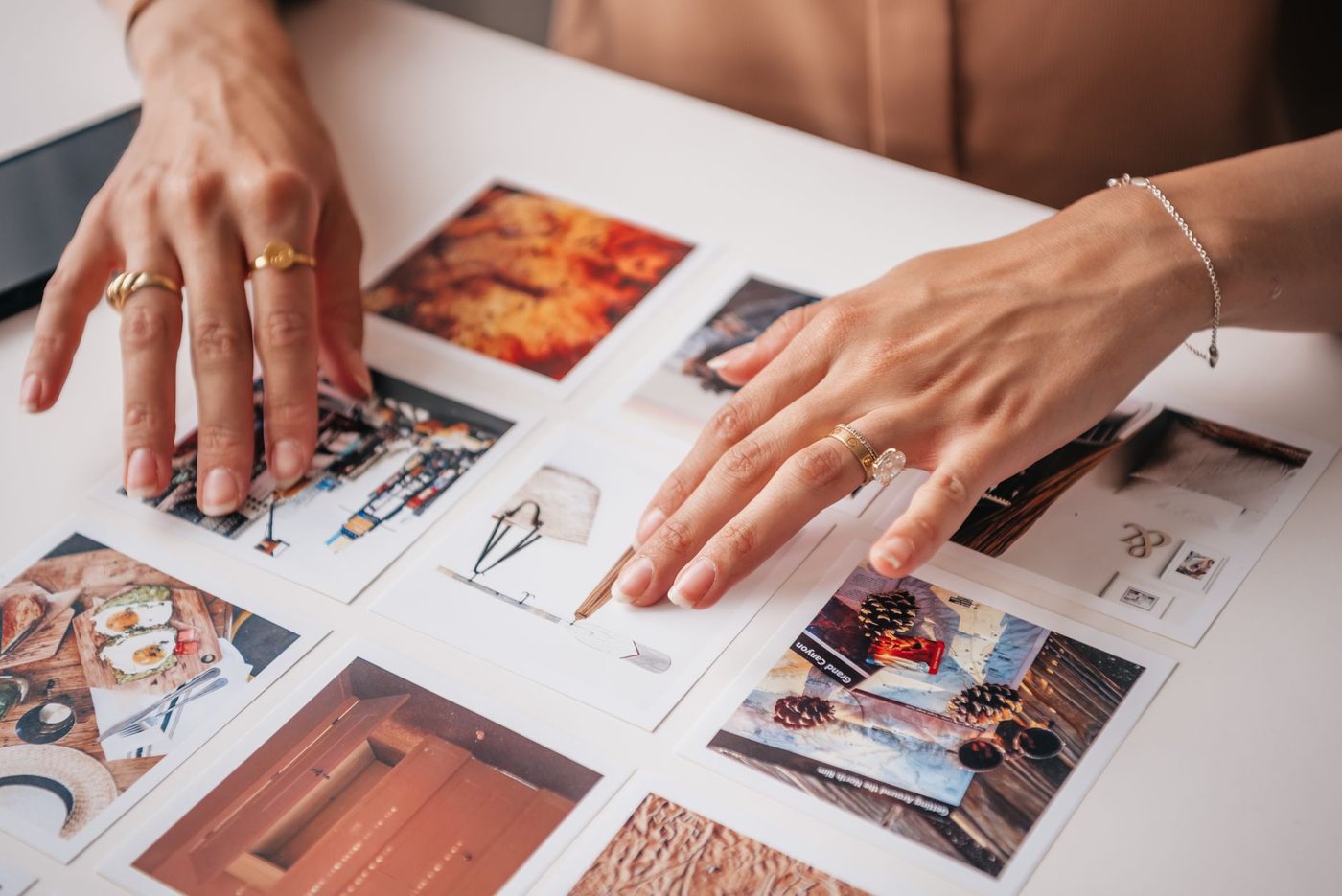 Hands moving printed photos around on a table to make a choice