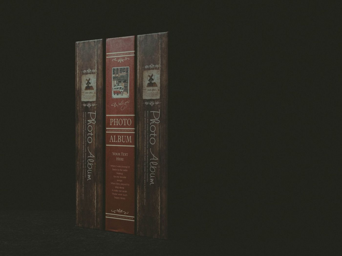 Three narrow album spines printed with Photo Album, a red one between two wood-coloured ones, against a dark background