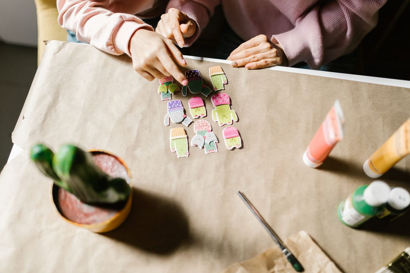 Several hands arranging paper cut-outs on a shared craft table