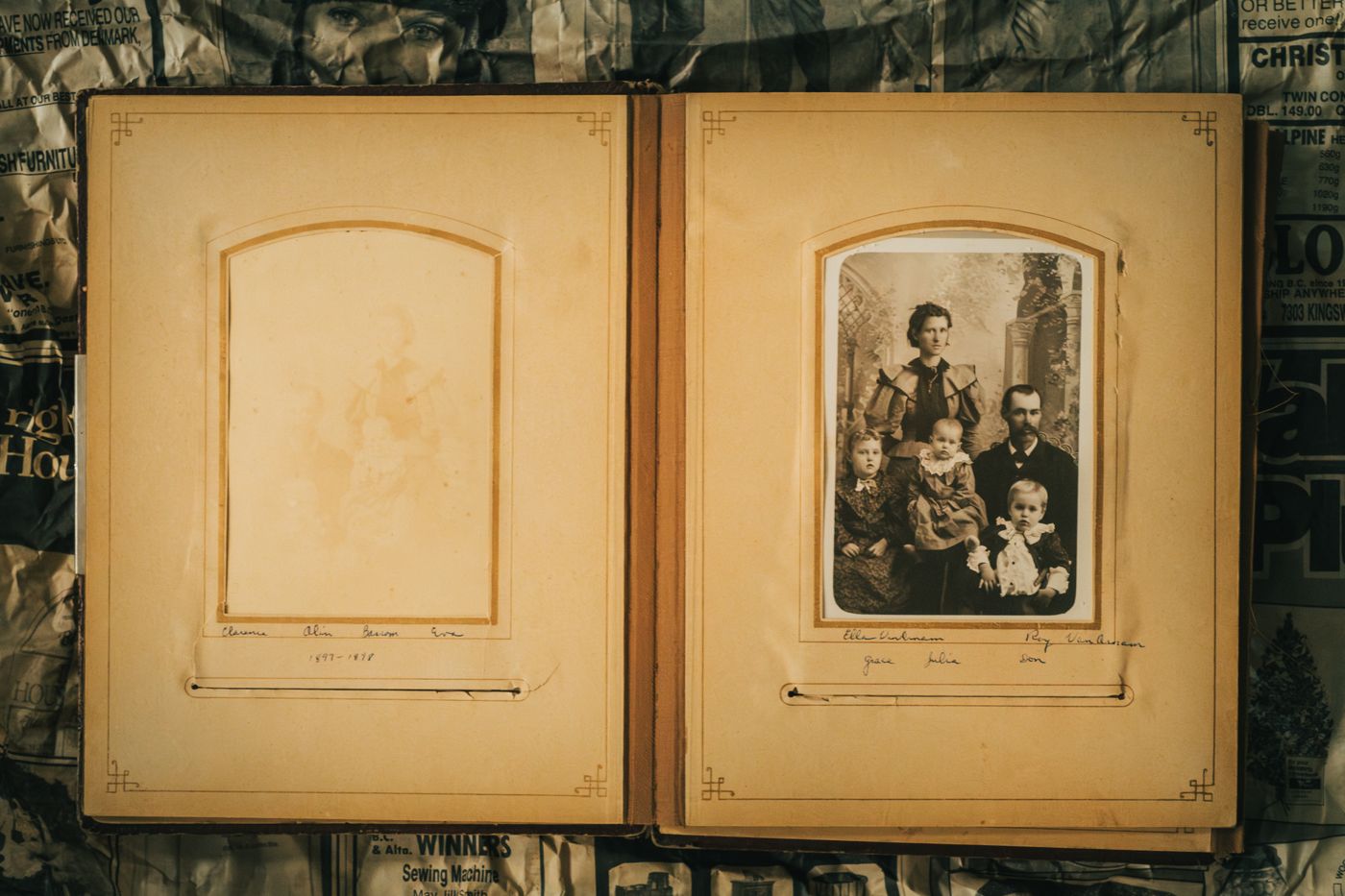Otvoren stari foto album: lijevo požutjeli, gotovo izblijedjeli portret, desno sepija fotografija obitelji